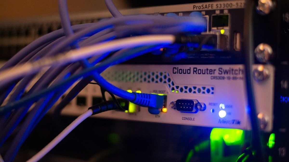 Ethernet cables plug into network equipment illuminated by blue status lights.