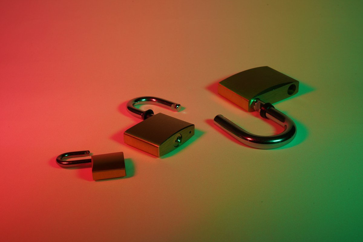 Open and closed brass padlocks under red and green lighting.